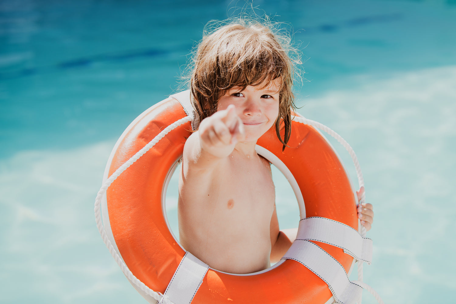 Child in a pool with an orange life buoy