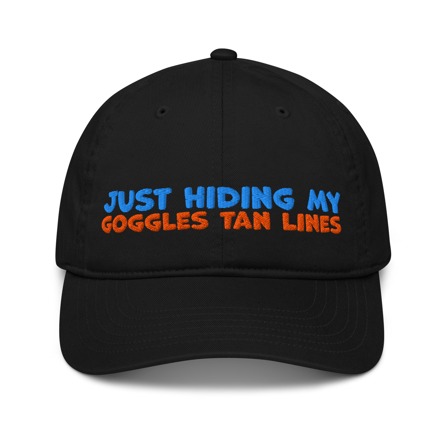 Black organic cotton baseball cap with "JUST HIDING MY GOGGLES TAN LINES" embroidered in blue and orange text.