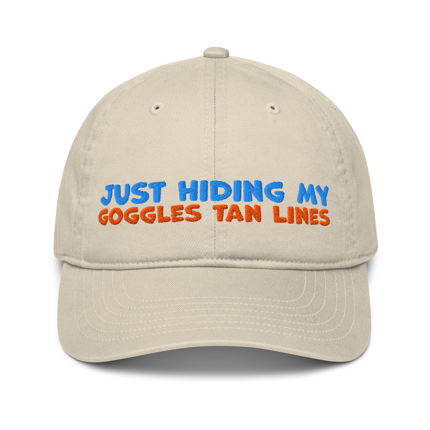Beige organic cotton baseball cap for swimmers with "JUST HIDING MY GOGGLES TAN LINES" embroidered in blue and orange text.