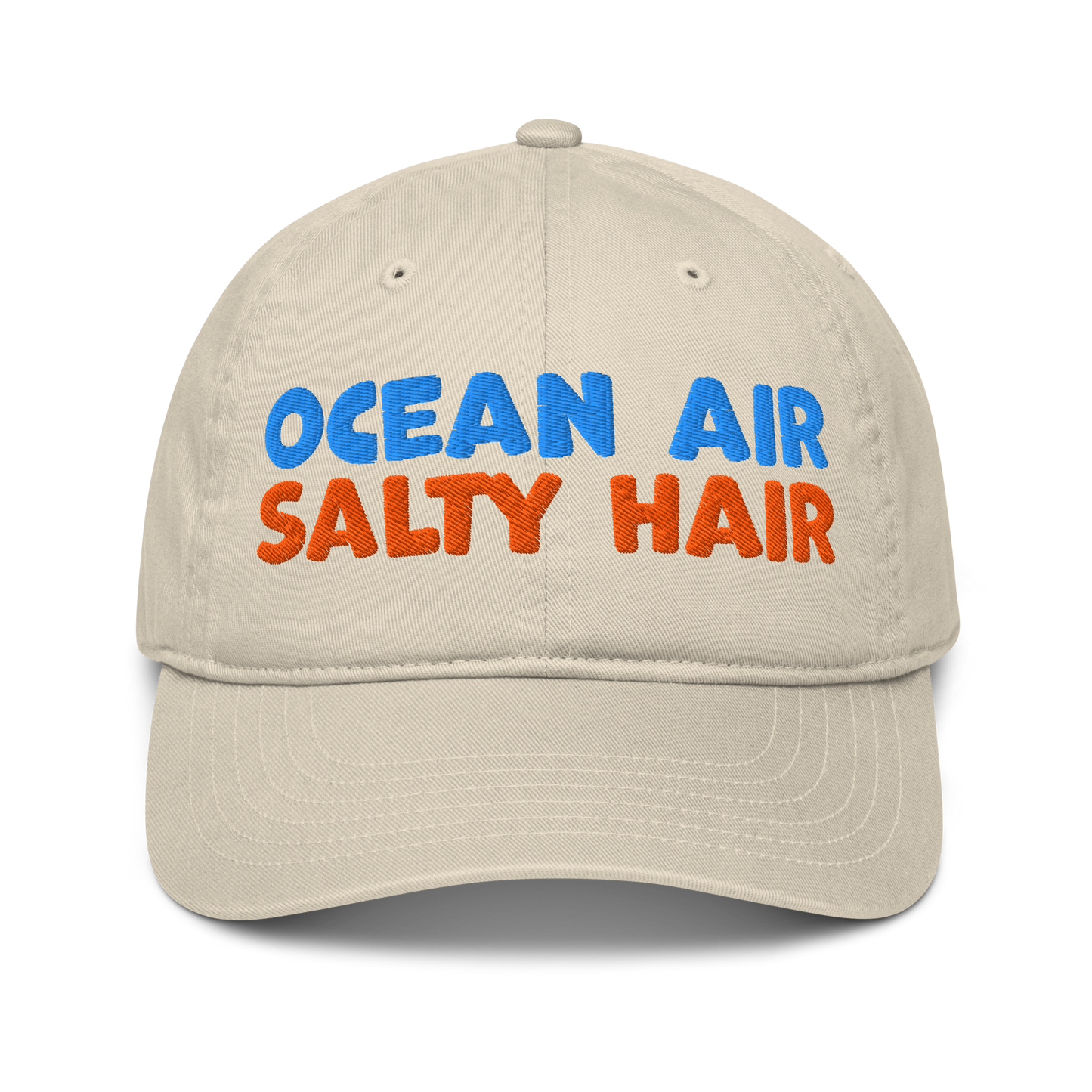 Beige organic cotton baseball cap with "OCEAN AIR" in blue and "SALTY HAIR" in orange embroidered text.