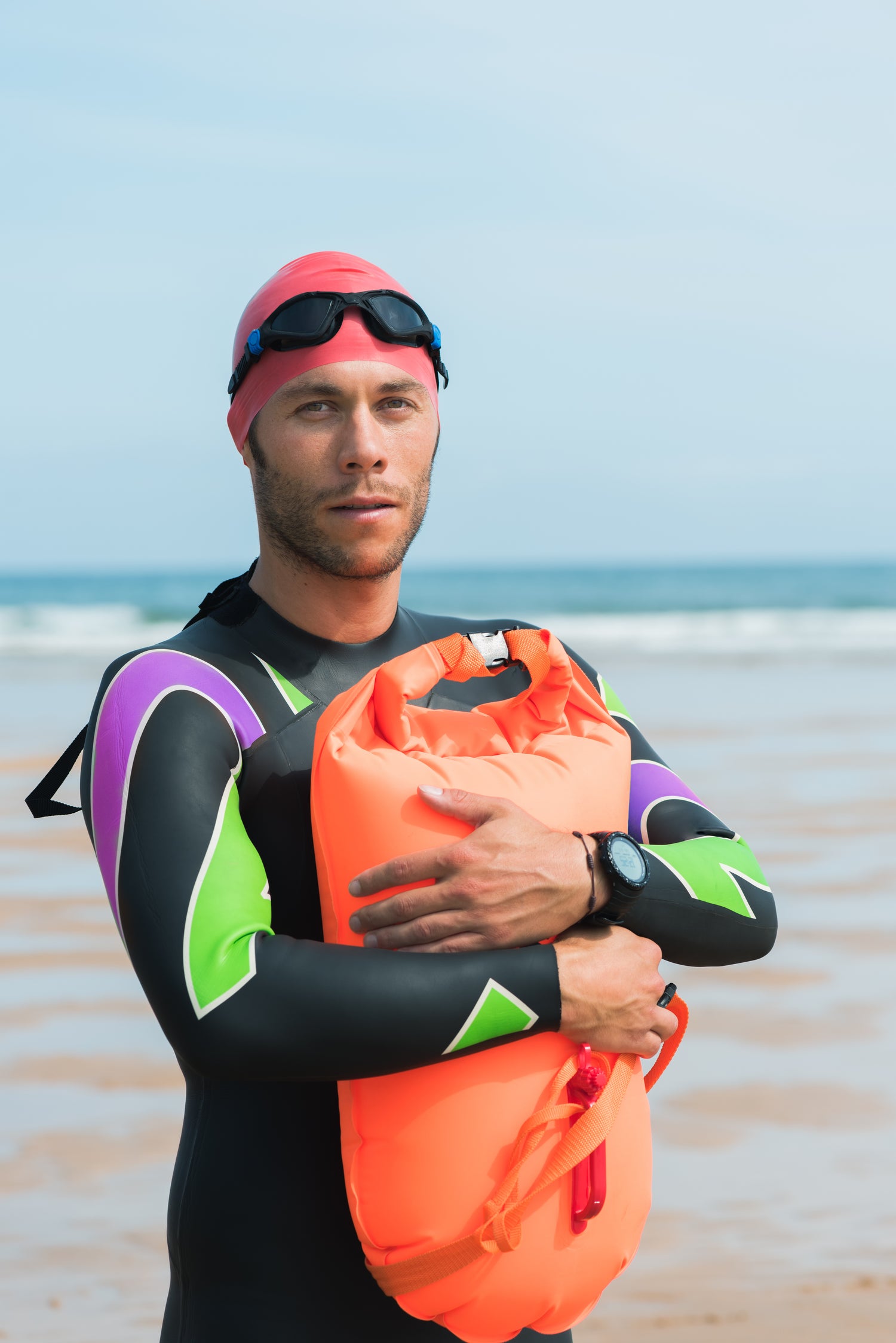 An open-water swimmer wearing a colorful swimsuit with a beach background