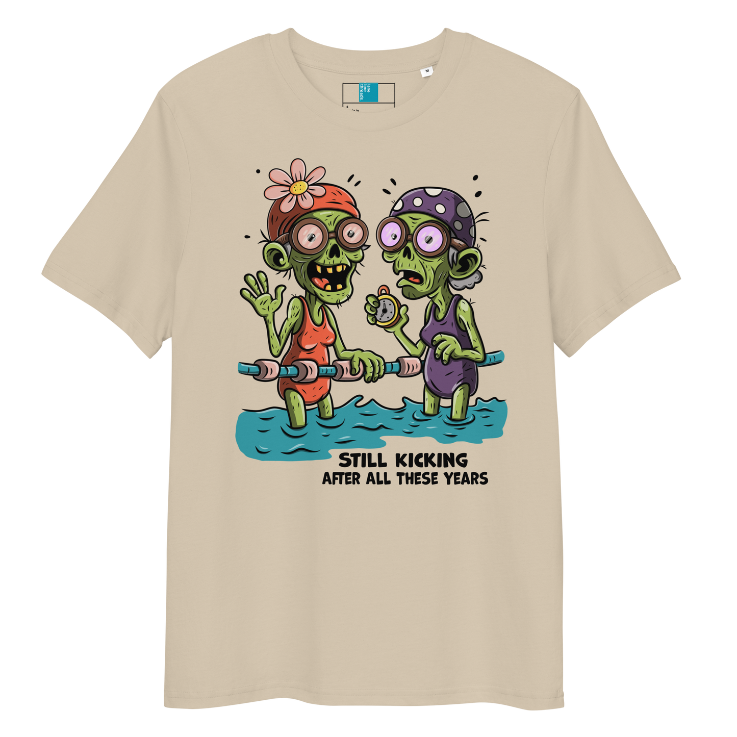 Beige organic cotton Halloween swim practice shirt with cartoon zombie swim besties holding lane line, text reads ‘still kicking after all these years'