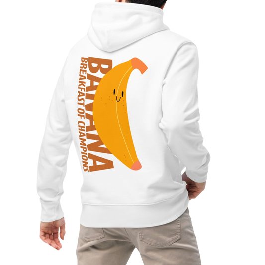 A person wearing an organic hoodie in white by Lane Line Threads with a smiling banana and "Banana Breakfast Champion" text graphic, made from GOTS and OCS certified organic cotton.