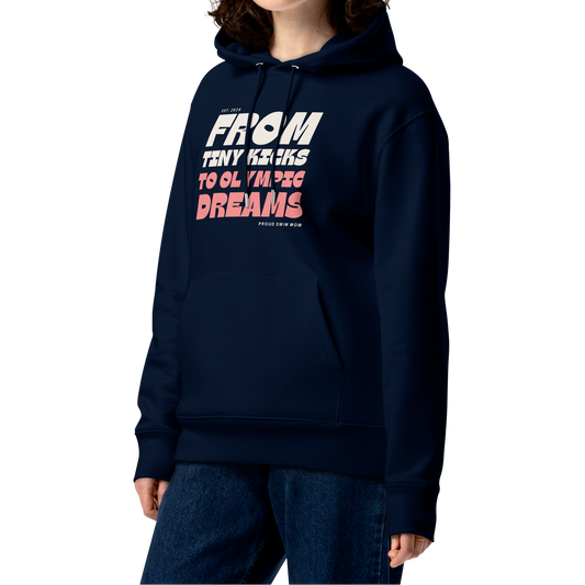 Person wearing a navy swim mom organic hoodie with “From Tiny Kicks to Olympic Dreams – Proud Swim Mom” text in white and pink; 100% organic certified cotton for eco‑conscious swim families.