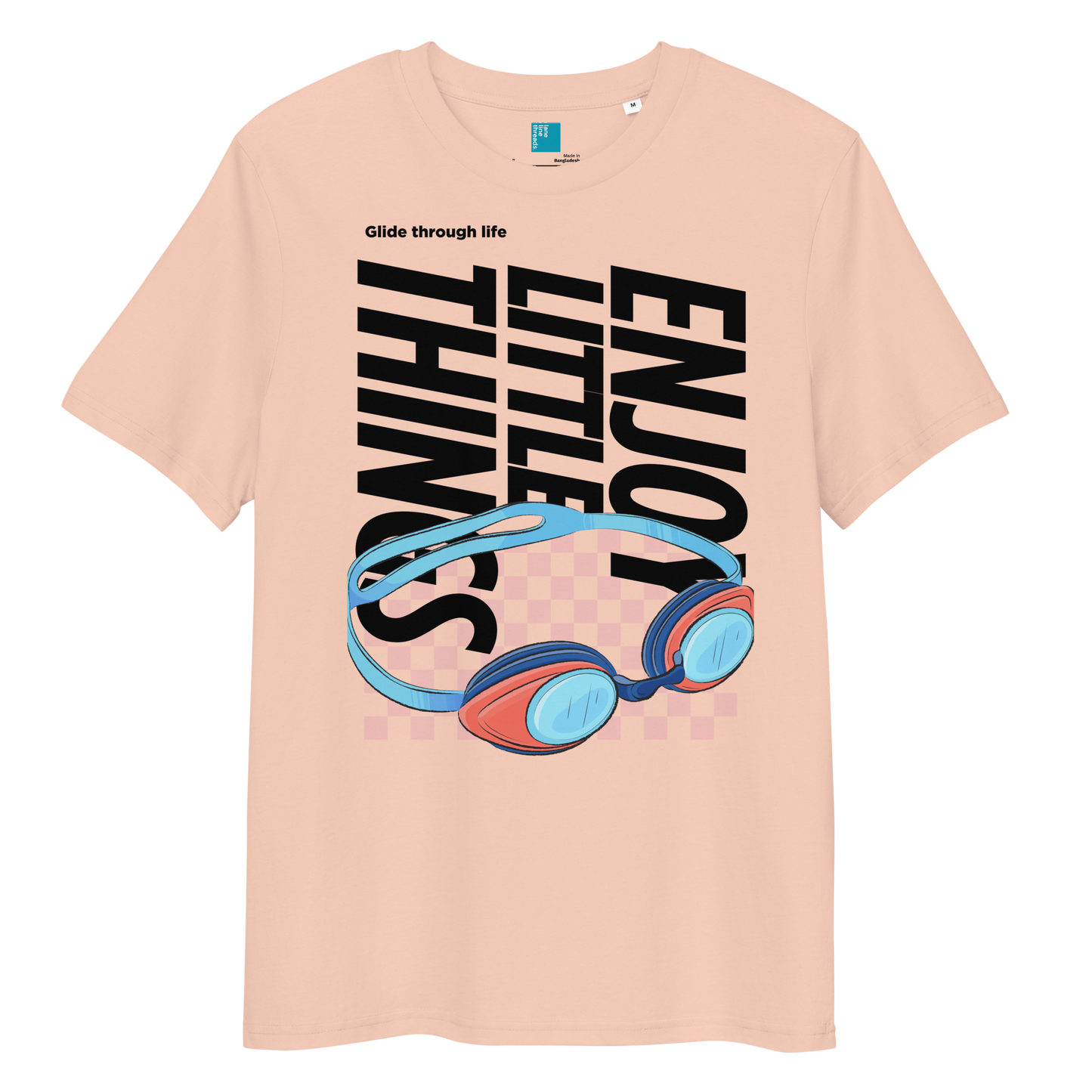 fraiche peche eco-friendly t-shirt featuring vibrant blue and red swimming goggles with a checkered background, and bold black text "ENJOY THE LITTLE THINGS" rotated vertically. Above the goggles, "Glide through life" is in smaller text. Made from 100% organic cotton, this breathable and biodegradable shirt is perfect for competitive swimmers who value comfort, performance, and sustainability. Ideal gift for swim meets or lane-protecting athletes with a sense of humor.