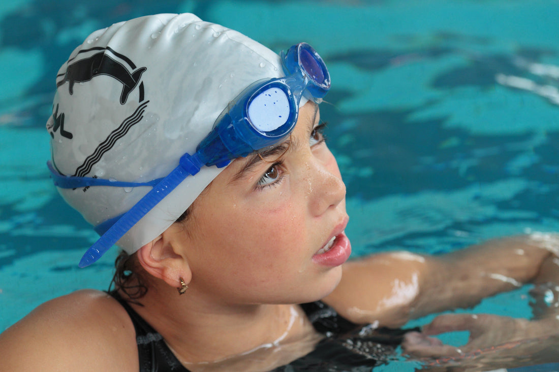 swimmer girl in the pool with swimming cap and goggles on her head