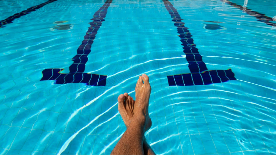 Relaxing feet in a swimming pool, highlighting the importance of a post-swim skin care routine.