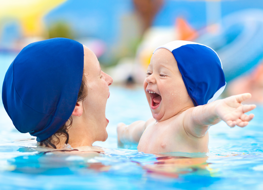 Woman and child wearing blue swim caps in a pool