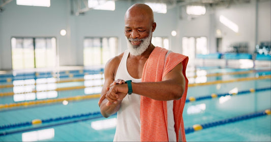 A retired swimmer in a tank top and towel checks his watch, embodying what retired swimmers wear