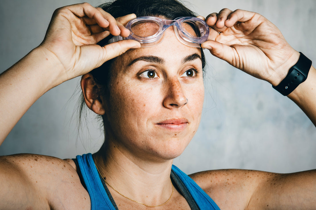 Person wearing swim goggles with a neutral background