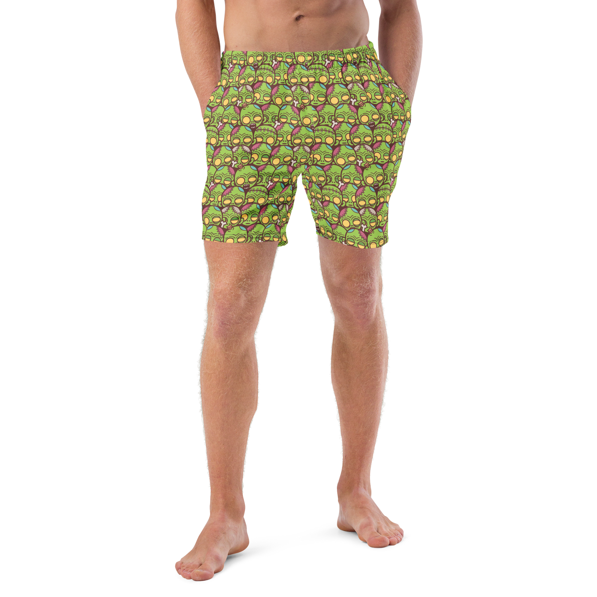 Person wearing green Halloween patterned recycled swim trunks on a white background