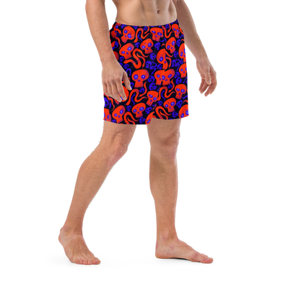Person wearing a Halloween themed organic swim trunks with skulls and snakes pattern on transparent background