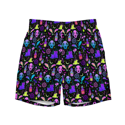 Colorful Halloween-themed organic swim trunks featuring skulls, moons, potions, and crystals on a black background; eco-friendly and designed for swimmers.