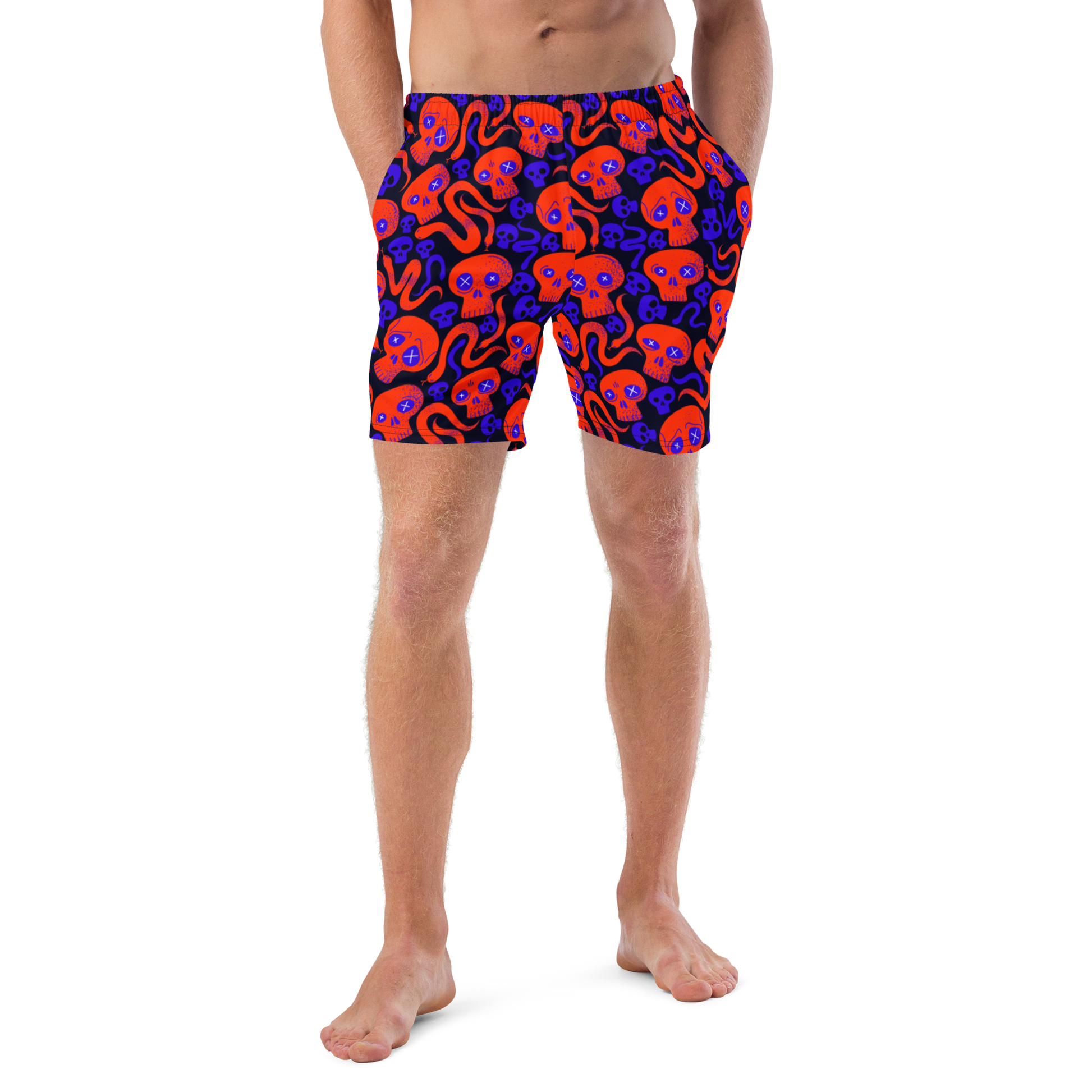 Person wearing Halloween themed organic swim trunks with a skulls and snakes pattern on a white background