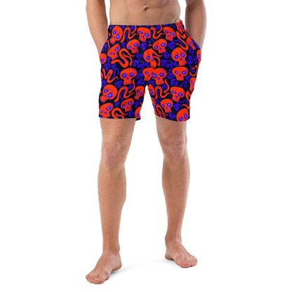 Person wearing Halloween themed organic swim trunks with a skulls and snakes pattern on a white background