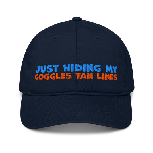 Navy blue organic cotton baseball cap for swimmers with "JUST HIDING MY GOGGLES TAN LINES" embroidered in blue and orange text.