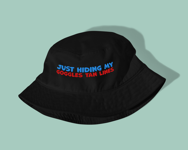 Black organic post-swim bucket hat with text 'Just hiding my goggles tan lines' on a light green background