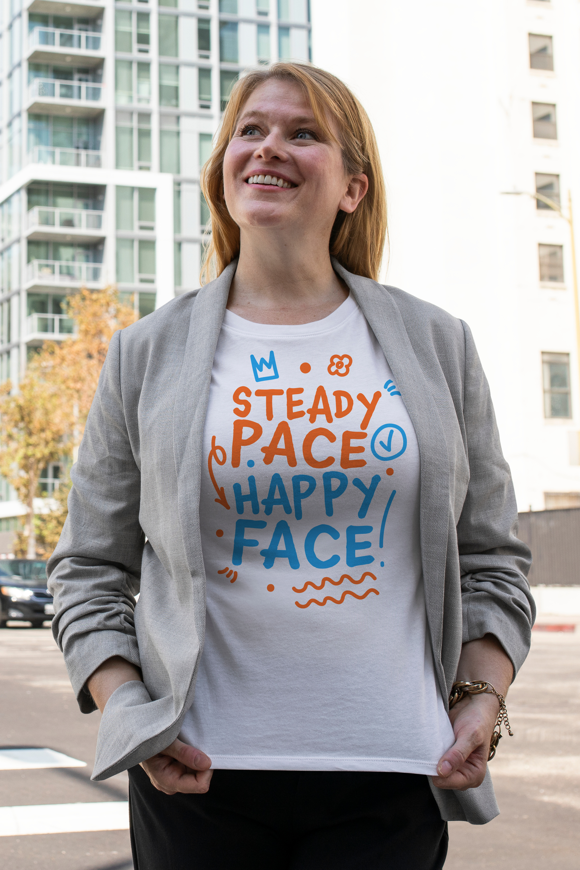 Woman wearing a white organic swim shirt with colorful text in an urban setting