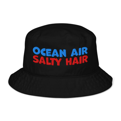Black organic cotton bucket hat with bold embroidery that reads “Ocean Air Salty Hair” in blue and red. Eco-friendly, breathable, and biodegradable.