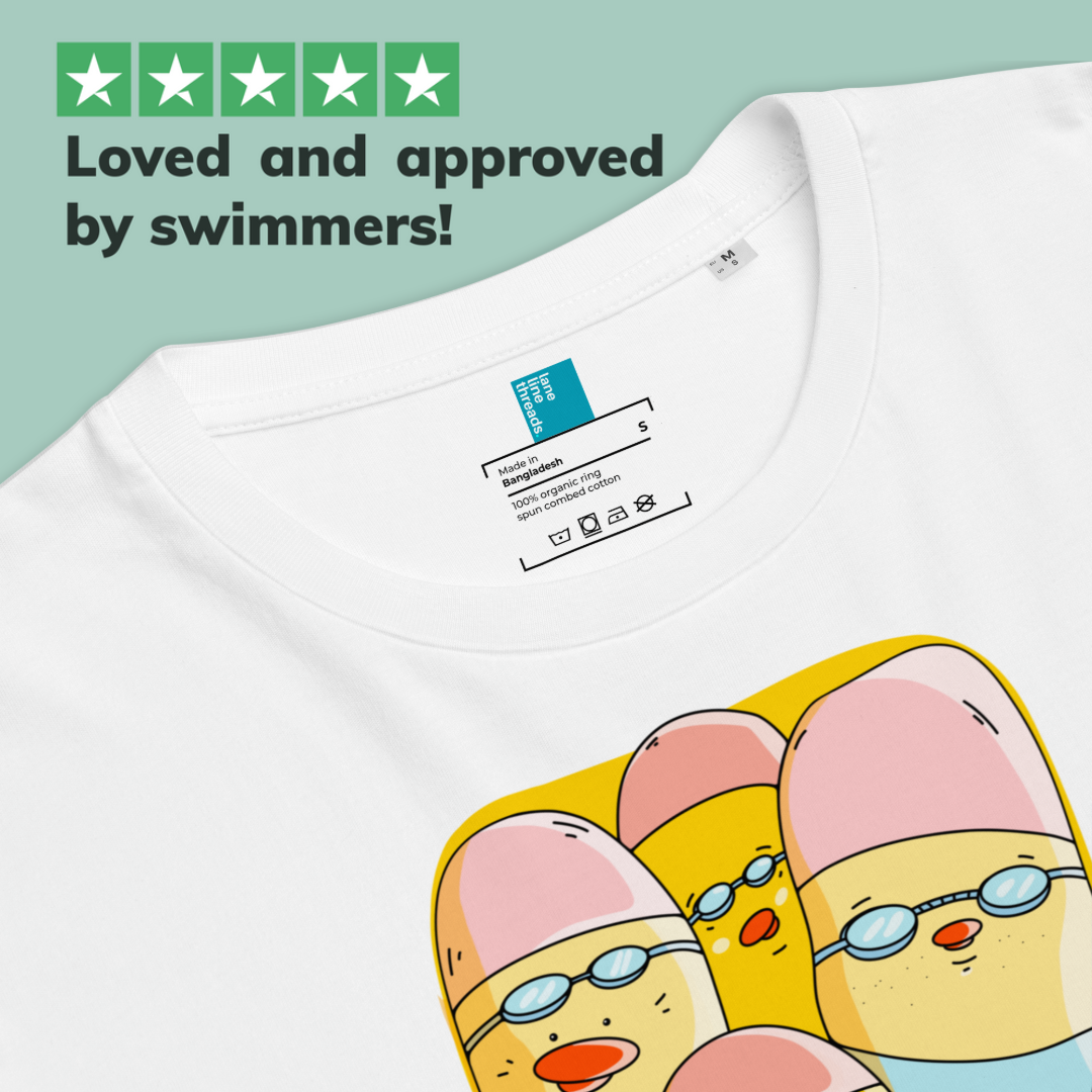 Close-up of a white short-sleeve organic cotton t-shirt showing the inner neck label and part of a cartoon graphic of three ducklings wearing swim goggles. Text at the top reads 'Loved and approved by swimmers!' with green star icons.