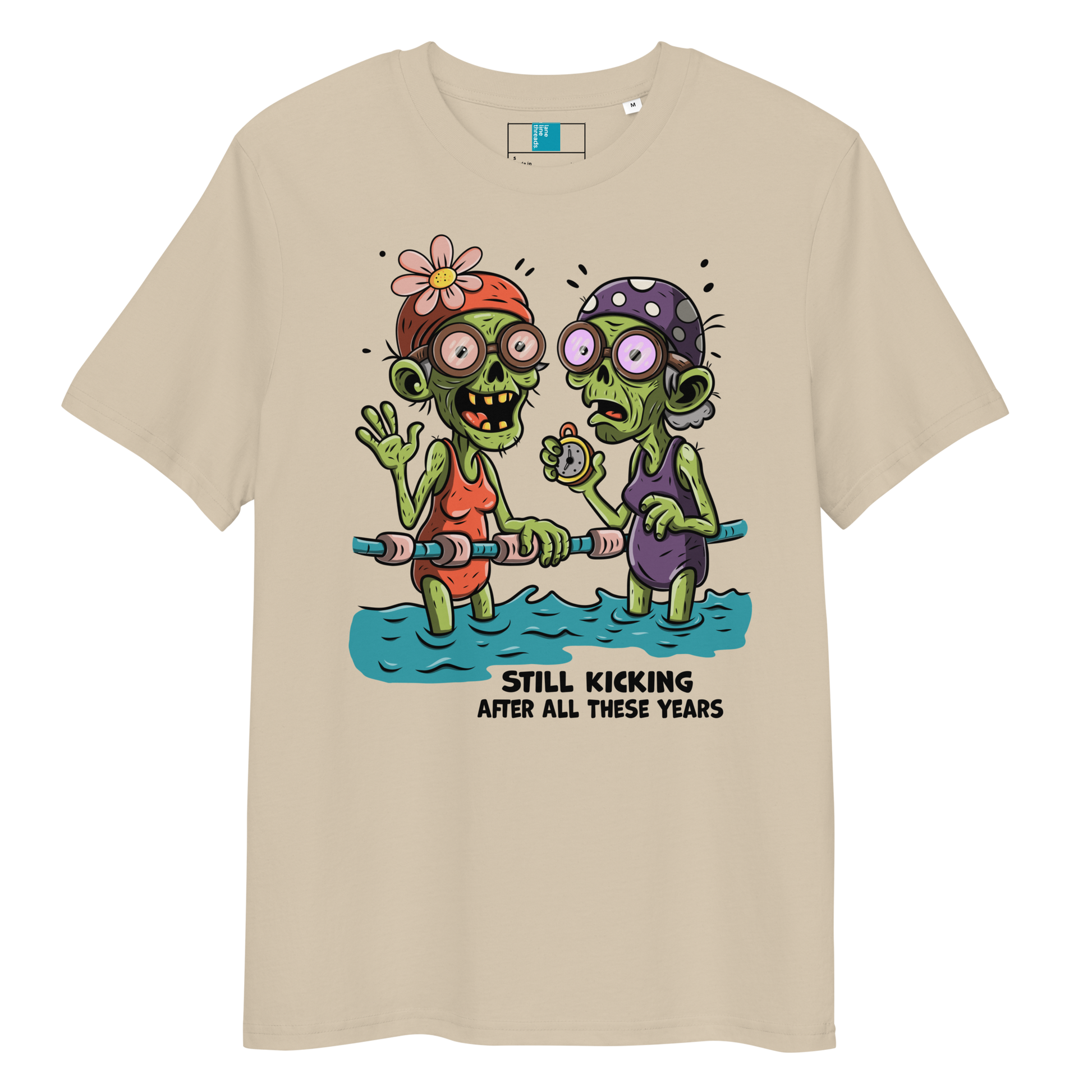 Beige organic cotton Halloween swim practice shirt with cartoon zombie swim besties holding lane line, text reads ‘still kicking after all these years'