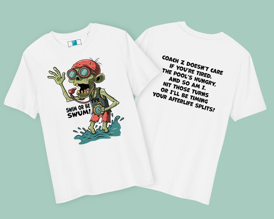 Two white organic Halloween swim-themed t-shirts laid flat on a light teal background. The left shirt features a cartoon zombie coach with red goggles and swim cap, holding a stopwatch in water, with the phrase “SWIM OR BE SWUM!” below. The right shirt shows bold black text on the back: “COACH Z DOESN’T CARE IF YOU’RE TIRED…” followed by a humorous, intense swim training message.