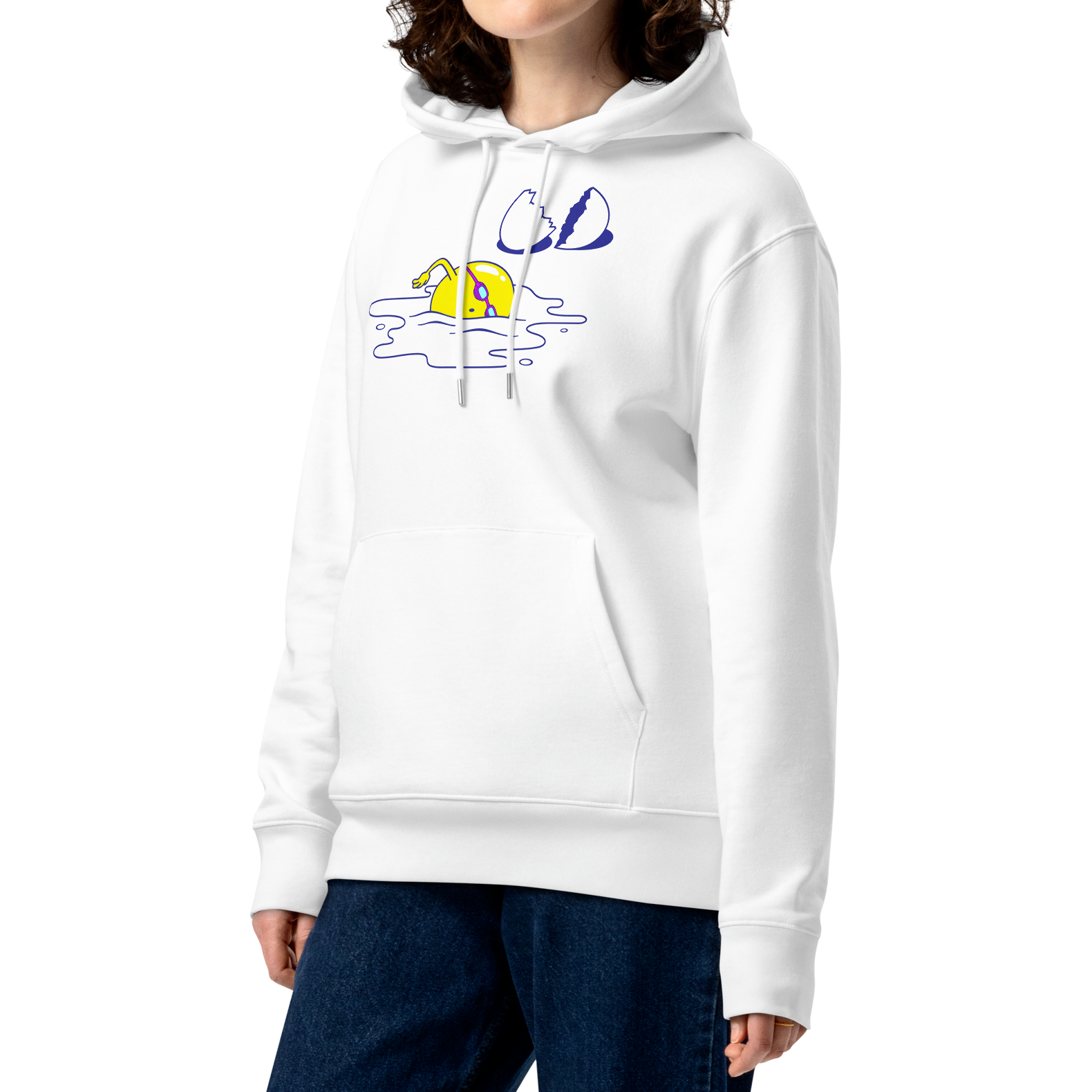 A female model with curly brown hair wearing an organic hoodie in white by Lane Line Threads featuring a graphic of a swimming yellow egg yolk with goggles and a cracked shell, paired with dark blue jeans, against a plain white background.
