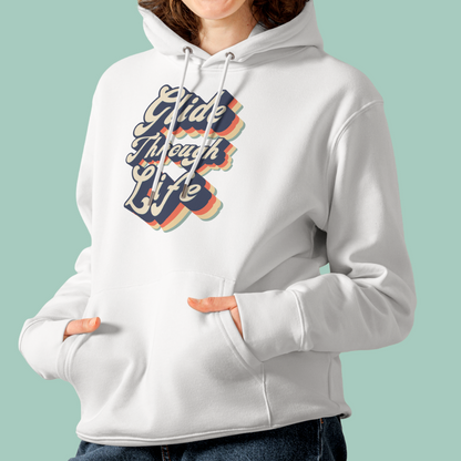 A person wearing a white pullover organic hoodie with a retro-style graphic on the chest that reads 'Glide Through Life' in layered navy, orange, yellow, and green tones, against a solid pale green background.