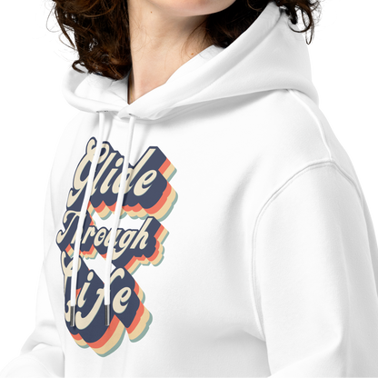 A woman with curly brown hair wearing an organic hoodie with "Glide Through Life" retro 3D typography on white GOTS and OCS certified cotton, designed for swimmer recovery
