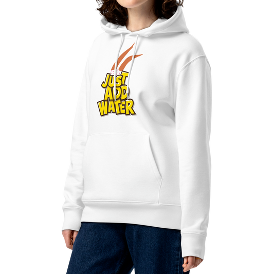 A woman with curly brown hair wearing an organic hoodie featuring a "Just Add Water" graphic with synchronized swimming legs on white GOTS certified organic cotton, paired with dark blue jeans, against a plain white background.