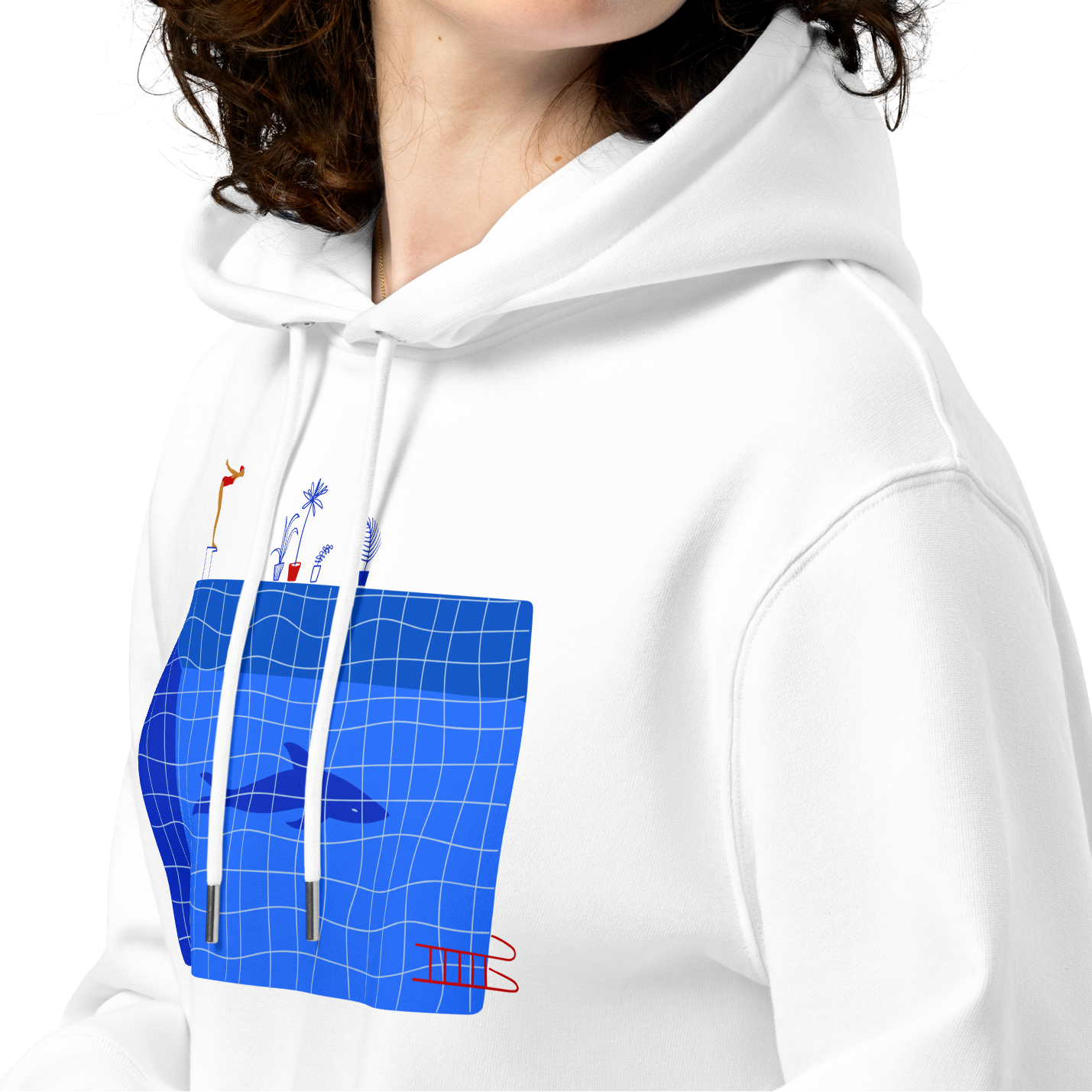 A woman with curly brown hair wearing an organic hoodie in white by Lane Line Threads featuring a graphic of a diver, potted plants, and a shark silhouette in a blue pool shown against a plain white background.