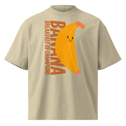 A beige short-sleeve crewneck organic oversized t-shirt by Lane Line Threads featuring a graphic print of a smiling yellow banana with the text 'BANANA BREAKFAST OF CHAMPIONS' in brown.