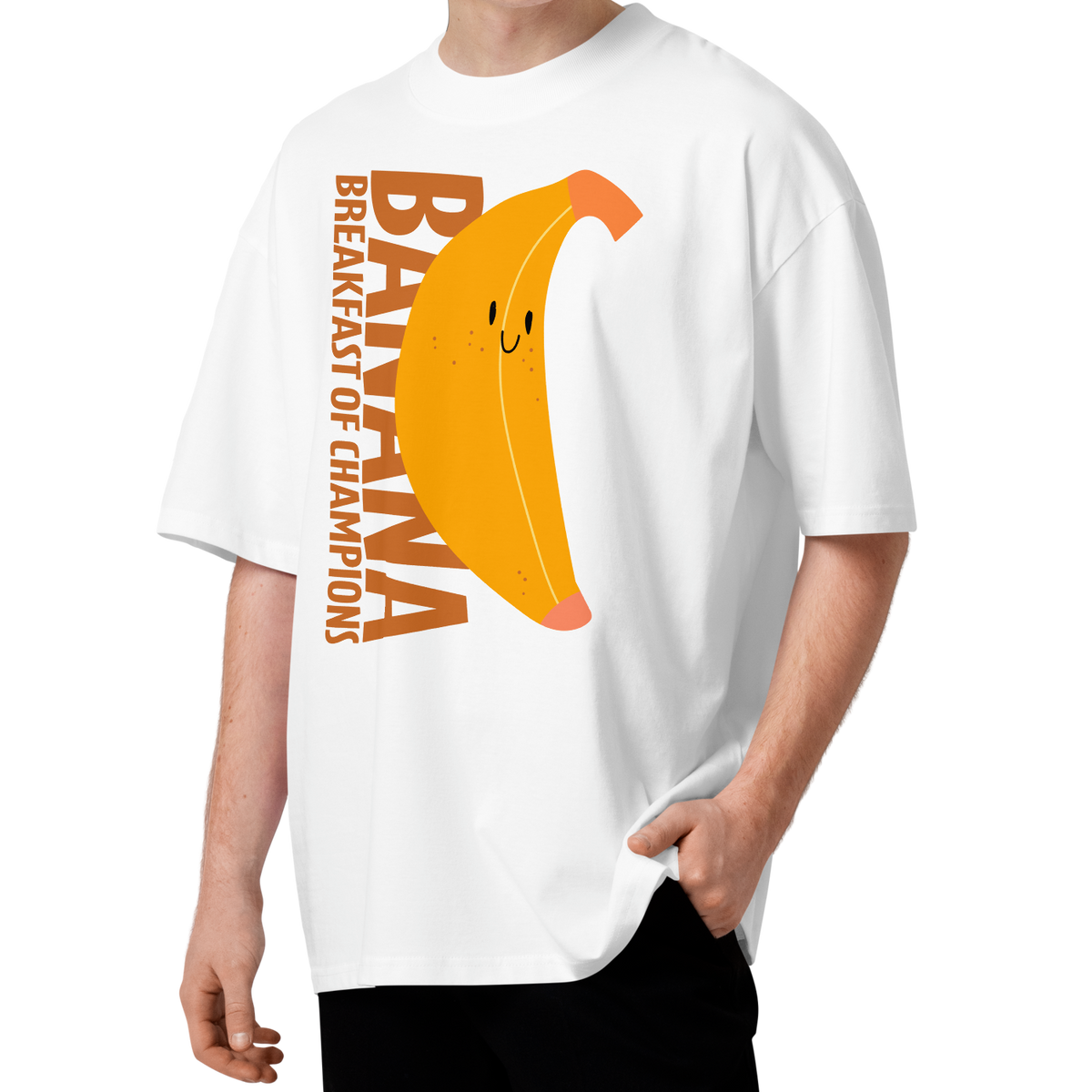 A young man with curly brown hair wearing a white short-sleeve crewneck organic oversized t-shirt by Lane Line Threads featuring a graphic print of a smiling yellow banana with the text 'BANANA BREAKFAST OF CHAMPIONS' in brown.