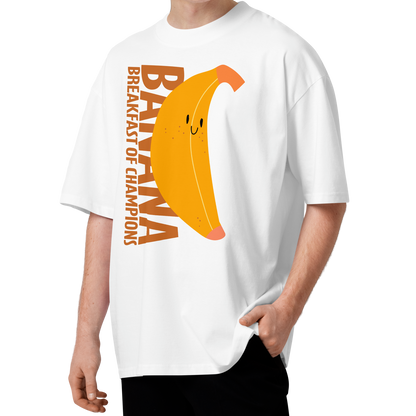 A young man with curly brown hair wearing a white short-sleeve crewneck organic oversized t-shirt by Lane Line Threads featuring a graphic print of a smiling yellow banana with the text 'BANANA BREAKFAST OF CHAMPIONS' in brown.