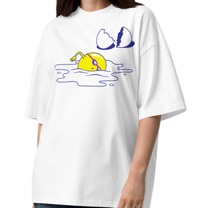 A woman modeling a white short-sleeve crewneck organic oversized t-shirt by Lane Line Threads featuring a graphic print of a yellow cartoon egg yolk swimmer character breaking an egg on a white background.