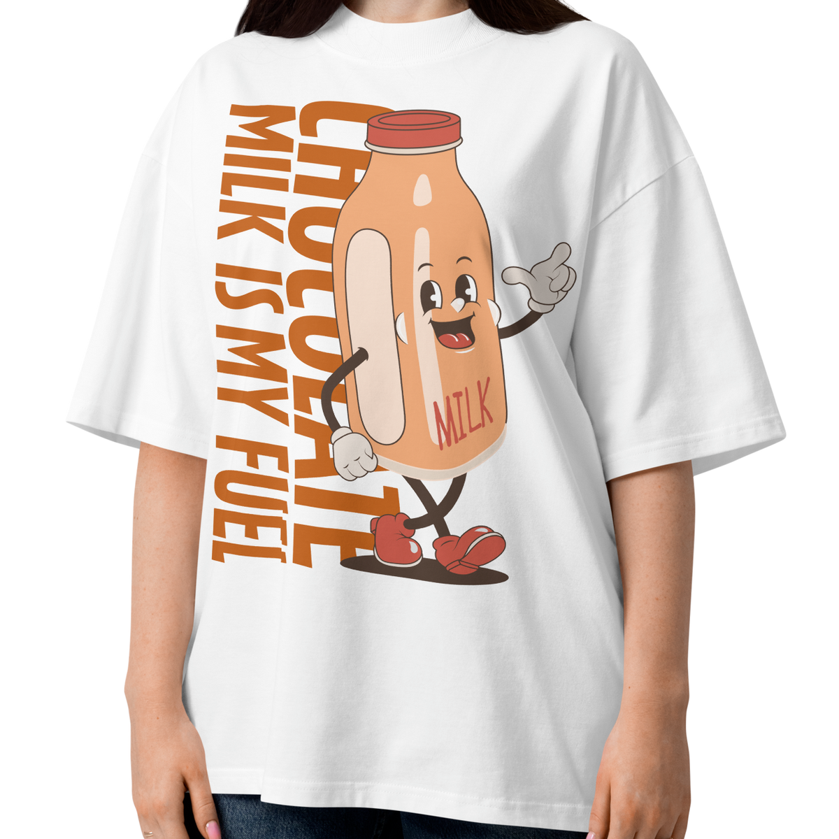 A woman wearing a white short-sleeve crewneck organic oversized t-shirt by Lane Line Threads featuring a cartoon graphic of a vintage milk bottle character with the text 'CHOCOLATE MILK IS MY FUEL' printed vertically in orange and inspired by Katie Ledecky.