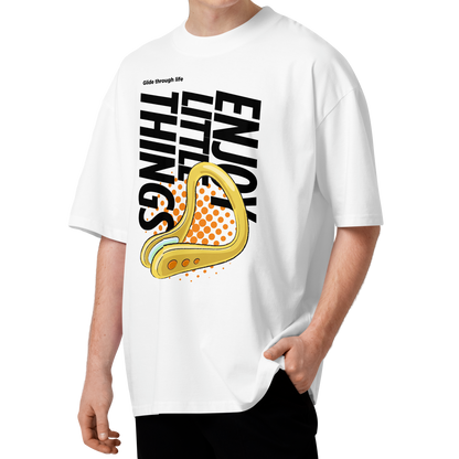 A man wearing a white short-sleeve crewneck organic oversized t-shirt by Lane Line Threads featuring a bold graphic print on the front. The design includes the text 'Enjoy Little Things' in black, a gold-colored swimming nose clip illustration, and a halftone pattern in orange.