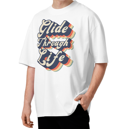 A young man with curly brown hair wearing an organic oversized t-shirt by Lane Line Threads in white with retro “Glide Through Life” layered swim graphic