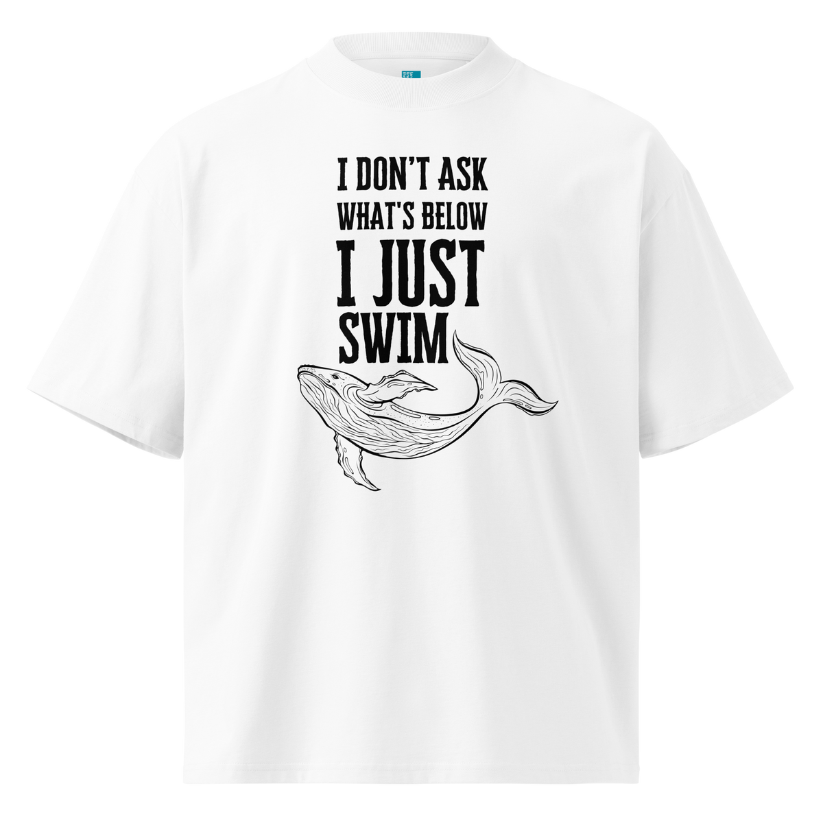 A white short-sleeve crewneck organic oversized t-shirt with a black graphic print on the front. The graphic features the text 'I DON'T ASK WHAT'S BELOW I JUST SWIM' above a black line art illustration of a whale.
