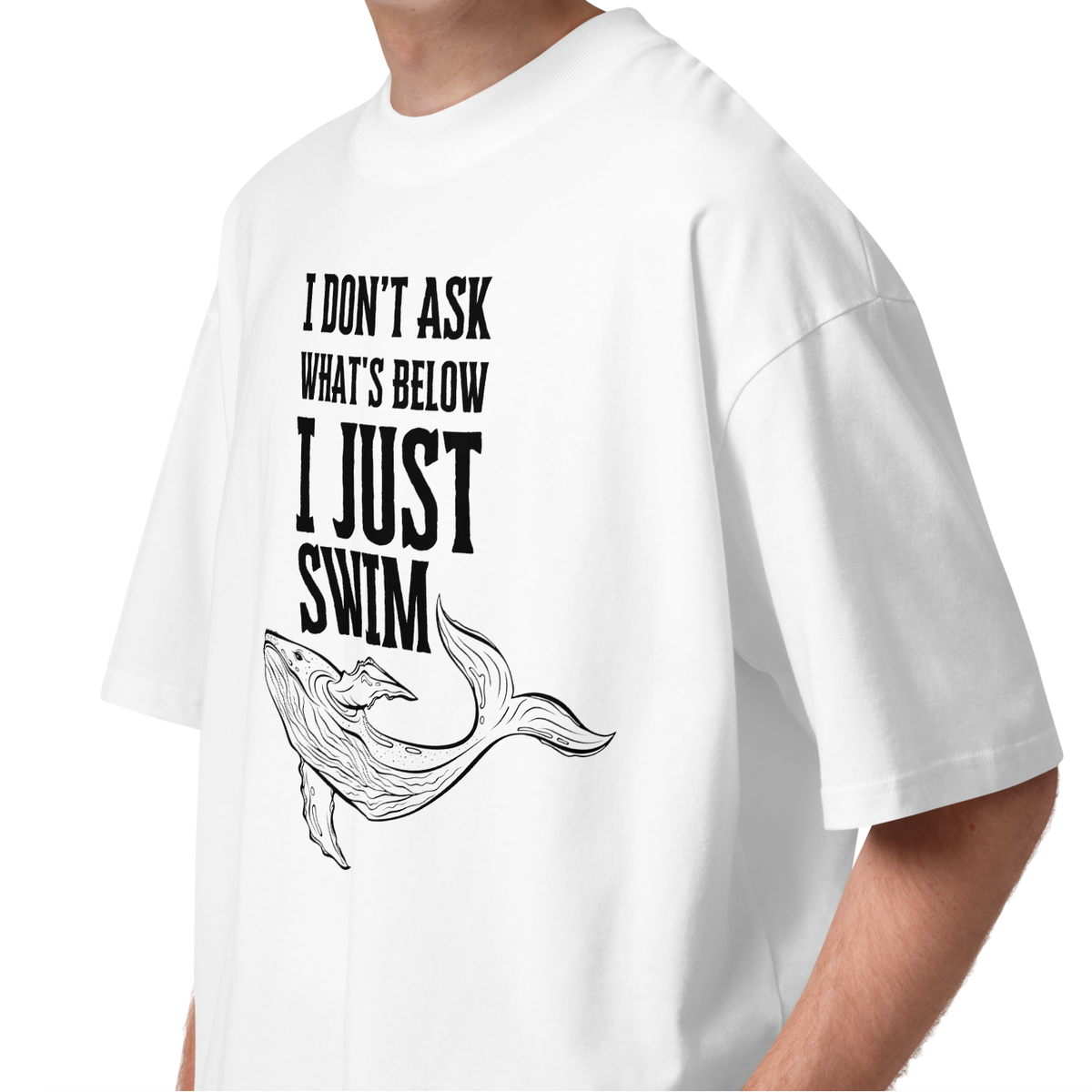 Person wearing an organic oversized t-shirt featuring a whale graphic and the phrase 'I JUST SWIM'.