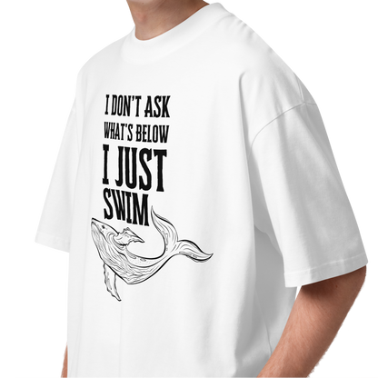 Person wearing an organic oversized t-shirt featuring a whale graphic and the phrase 'I JUST SWIM'.