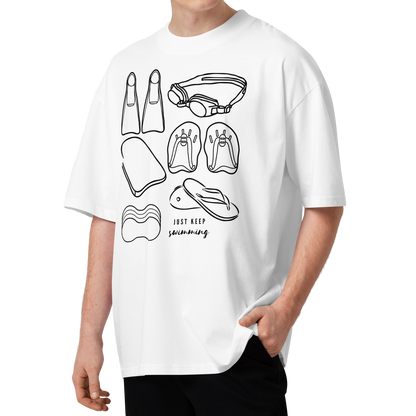 A man wearing a white organic oversized t-shirt with a black line art graphic of various swimming accessories and the text 'JUST KEEP swimming' on the front, paired with black pants, set against a plain white background.