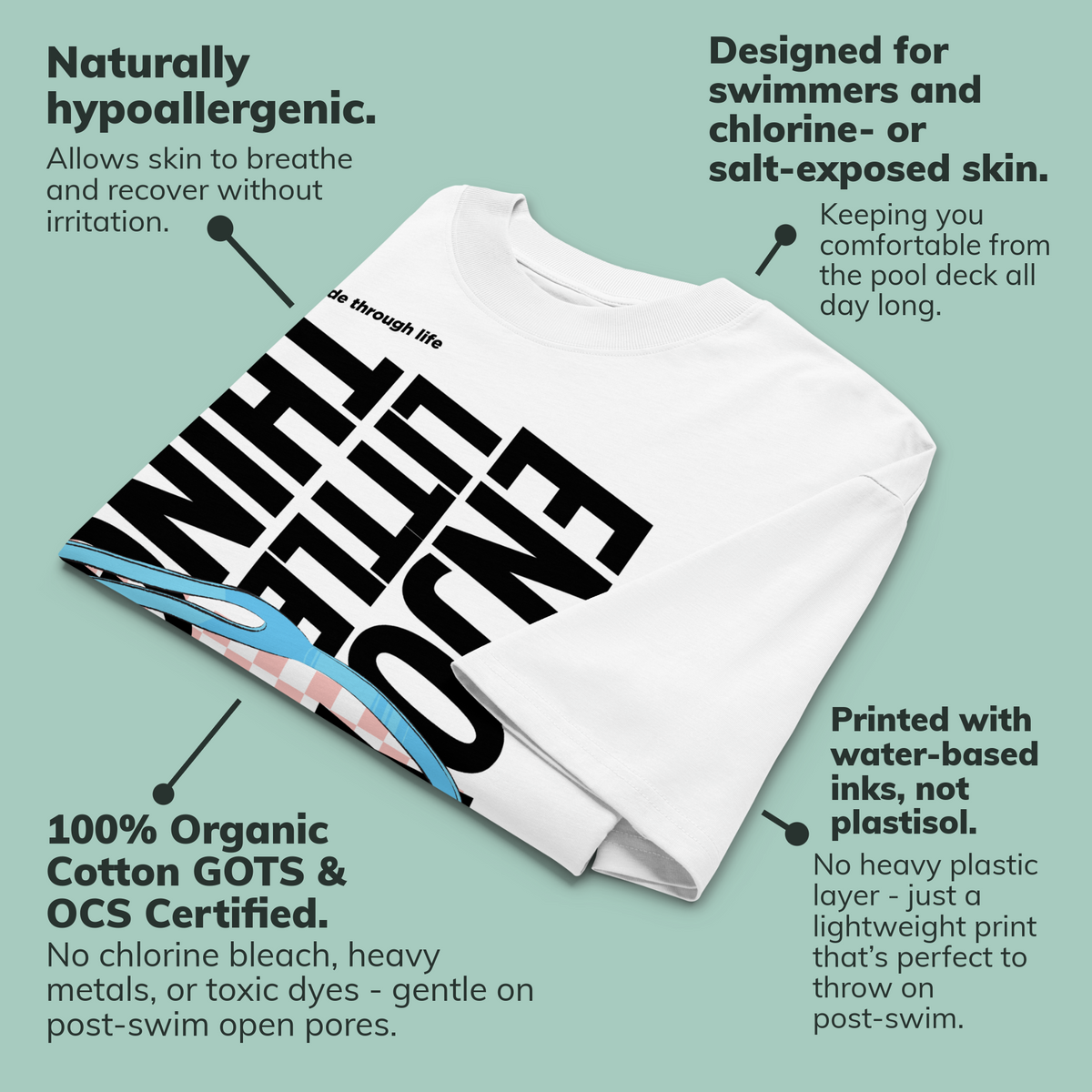 Folded organic oversized t-shirt in white with colorful swim goggles, bold “Enjoy Little Things” lettering, and “Glide Through Life” graphic by Lane Line Threads, showing callouts with product benefits.