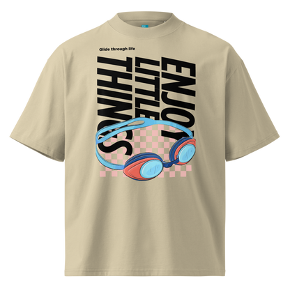 Organic oversized t-shirt in beige with colorful swim goggles, bold “Enjoy Little Things” lettering, and “Glide Through Life” graphic by Lane Line Threads.