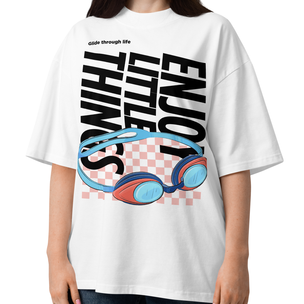 a young women wearing an organic oversized t-shirt in white with colorful swim goggles, bold “Enjoy Little Things” lettering, and “Glide Through Life” graphic by Lane Line Threads.