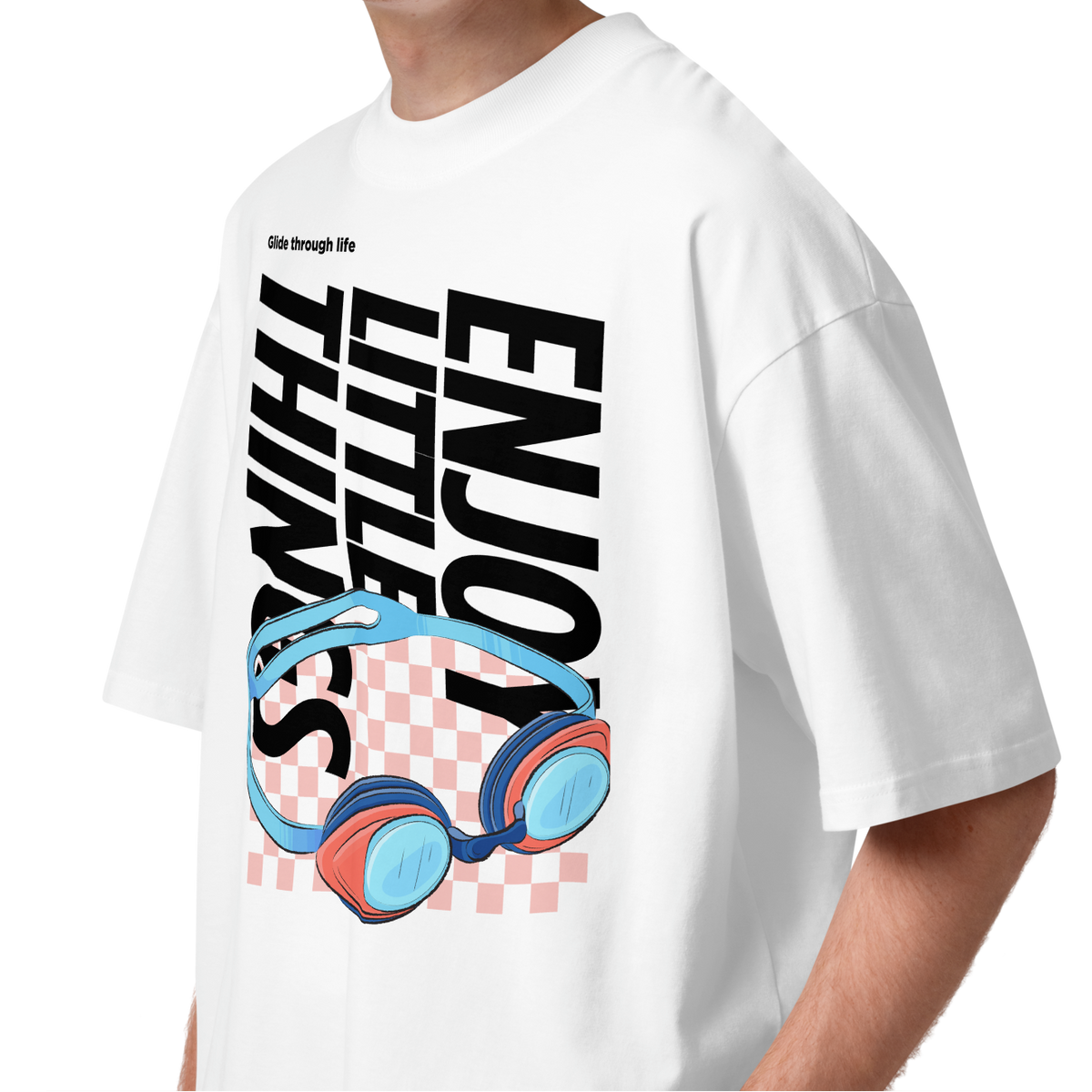 a young man wearing an organic oversized t-shirt in white with colorful swim goggles, bold “Enjoy Little Things” lettering, and “Glide Through Life” graphic by Lane Line Threads.