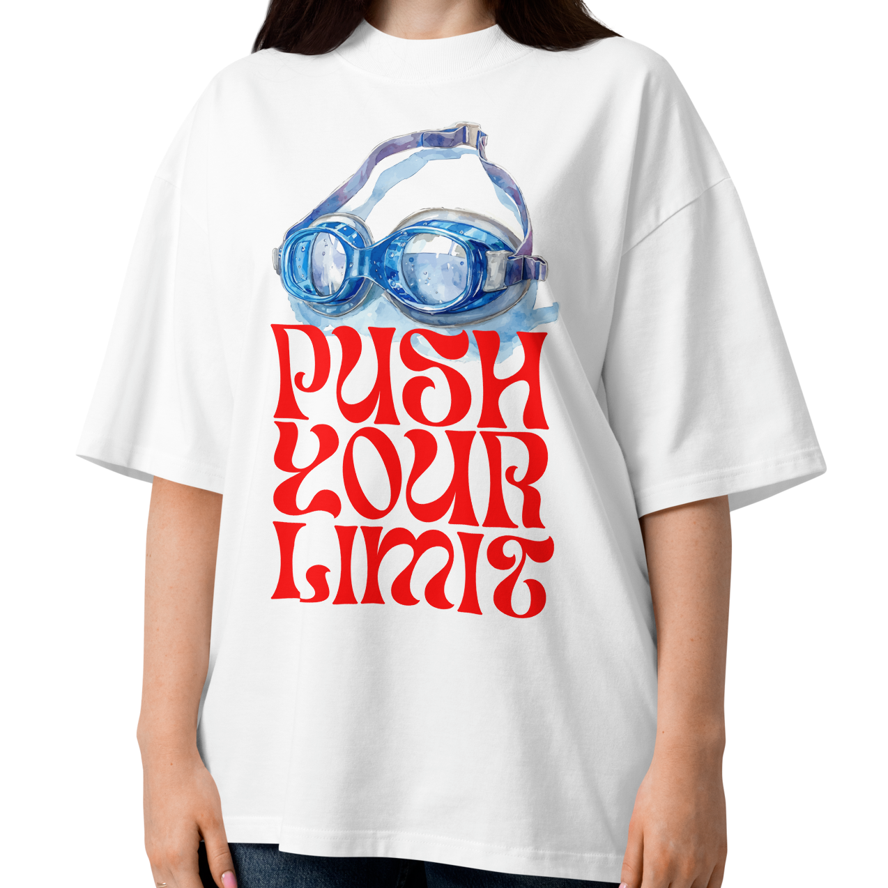 A woman wearing a white organic oversized t-shirt by Lane Line Threads with a blue swim goggles and red 'PUSH YOUR LIMIT' text design, paired with blue jeans, against a plain white background.