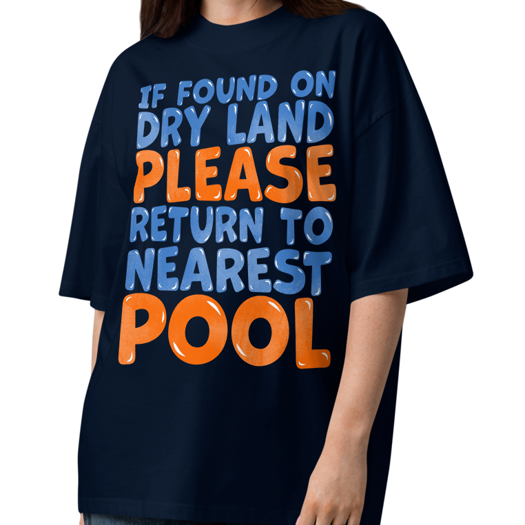 A woman modeling a navy blue organic oversized t-shirt with a bold text graphic that reads 'IF FOUND ON DRY LAND PLEASE RETURN TO NEAREST POOL' in light blue and orange lettering, paired with wide-leg jeans and sandals on a white background.