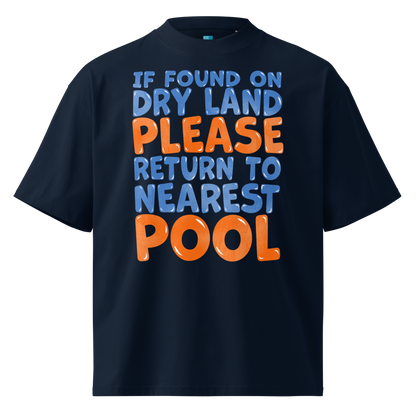 A navy blue short-sleeve organic oversized t-shirt with a bold graphic text print on the front reading 'IF FOUND ON DRY LAND PLEASE RETURN TO NEAREST POOL' in light blue and orange lettering, shown against a plain white background.