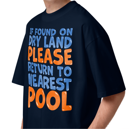 A young man wearing a navy-blue organic oversized t-shirt with a humorous slogan printed on the front in blue and orange text, set against a plain white background.